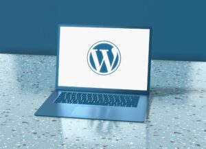 Ein Laptop steht auf einem Tisch, auf dessen Bildschirm das WordPress-Logo zu sehen ist.