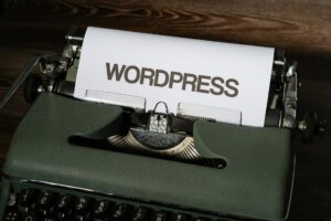 Eine alte Schreibmaschine mit einem Blatt Papier, auf dem „WordPress” geschrieben steht.